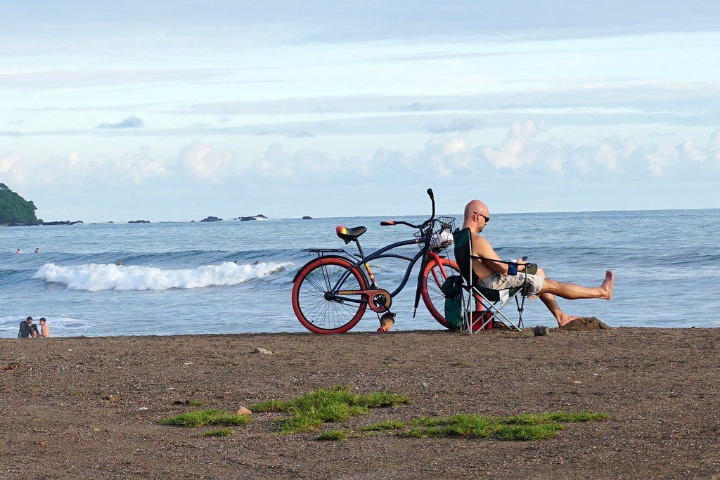 Costa Rica in November has perfect beach weather. Man on beach with bike